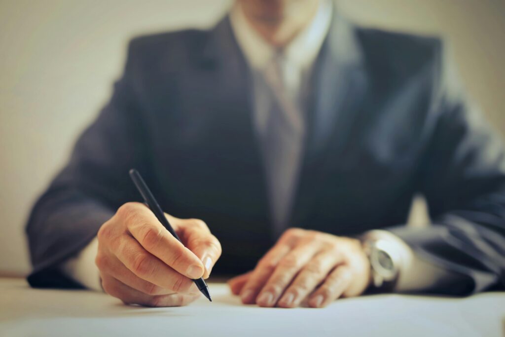 pexels-photo-3771097-3771097 Faceless businessman in suit signing a contract at office desk, focused on task.