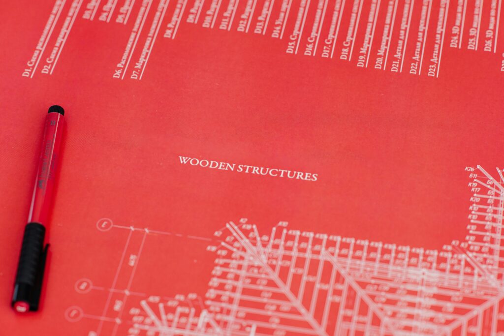 pexels-photo-4491831-4491831 Close-up of a red architectural blueprint showcasing wooden structures.