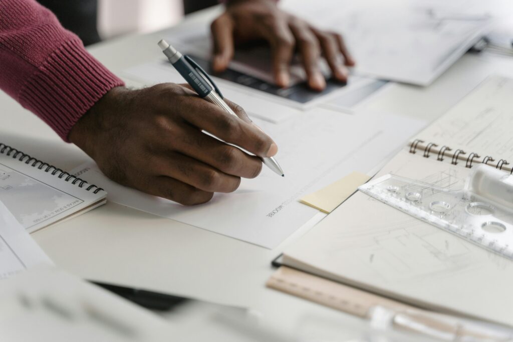 pexels-photo-6615294-6615294 Close-up of architect drafting on blueprints in a modern office environment.