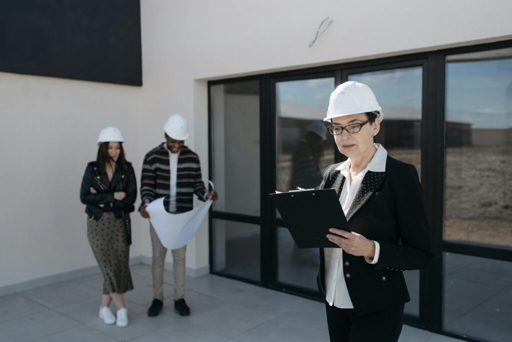 pexels-photo-7937709-7937709 Architects in hard hats examining construction plans at a building site.