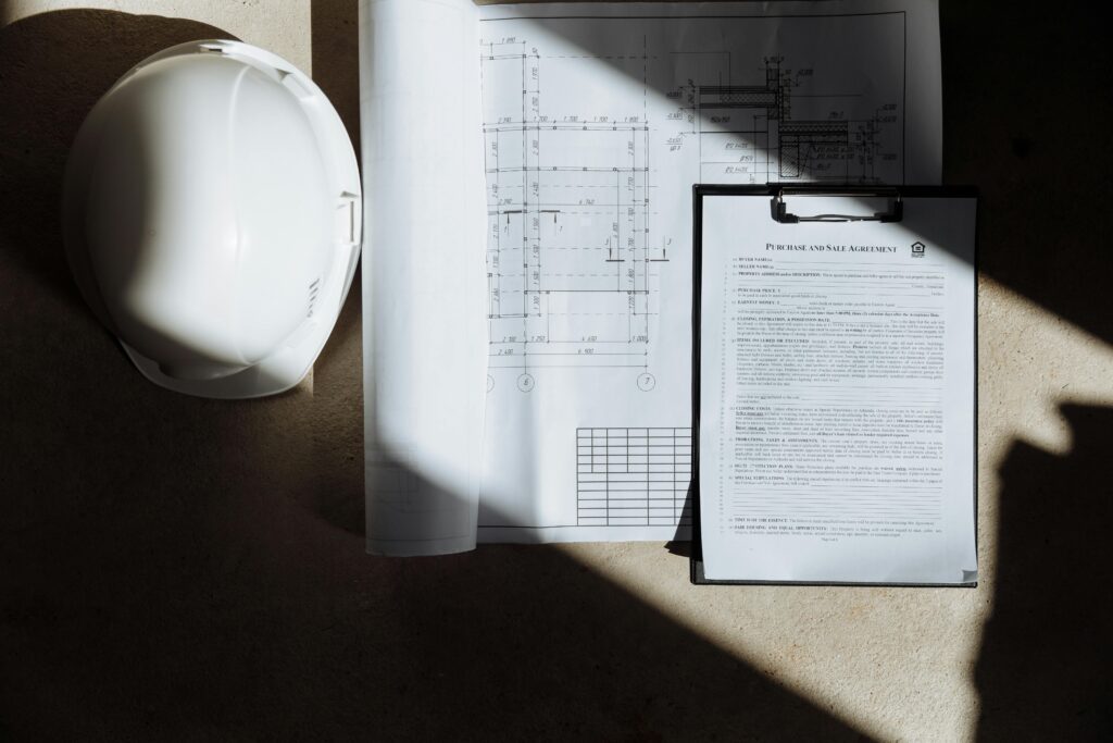 pexels-photo-8470057-8470057 Top view of construction documents and hard hat in sunlight, capturing planning essence.